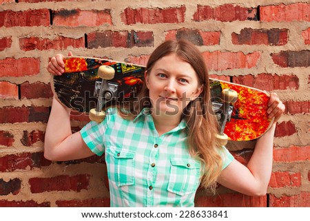Woman with skateboard against brick wall