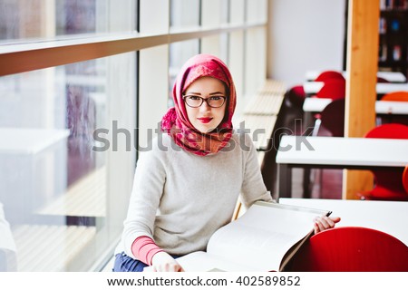 Woman in red head scarf read book sitting near window