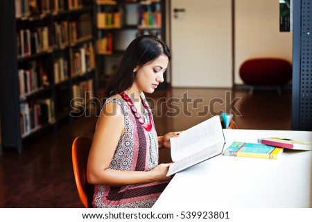 Indian student reads a book at the library, indoor