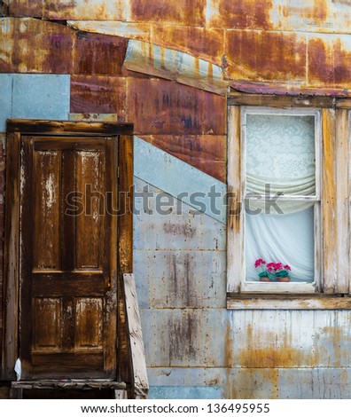 Rusted wall with antique door and flowers in the window
