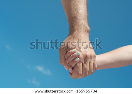 A young female person holding hands with an older male person close up outdoors