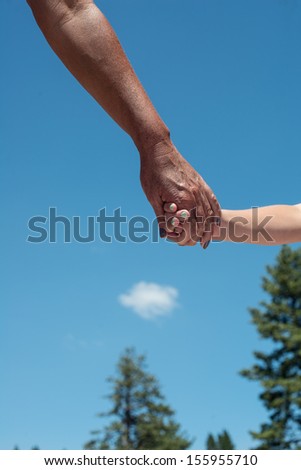 A young female person holding hands with an older female person close up outdoors