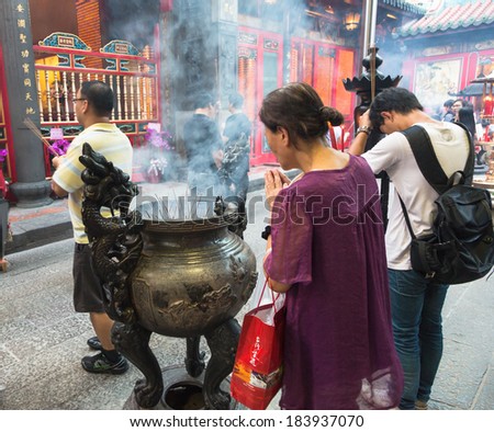 Taipei, Taiwan - July 27 2013: People pray in front burning incense sticks in a Buddhist temple in Taipei.