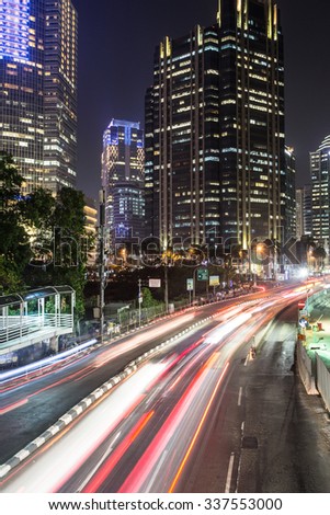 Traffic at night in Jakarta, along Indonesia capital city main avenue lined with banks , hotel and luxury shopping malls (Jalan Sudirman) in the business district