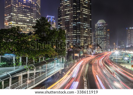 Traffic at night in Jakarta, along Indonesia capital city main avenue lined with banks , hotel and luxury shopping malls (Jalan Sudirman) in the business district