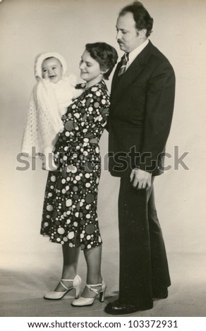 Vintage photo of god parents with a baby girl (seventies)