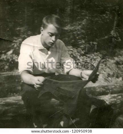 Vintage photo of young man reading a newspaper outdoor (early sixties)