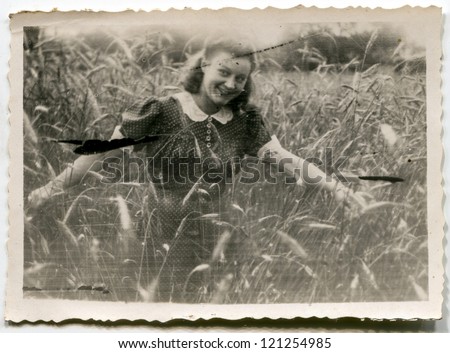 Vintage very grunge photo of young woman in wheat (forties)