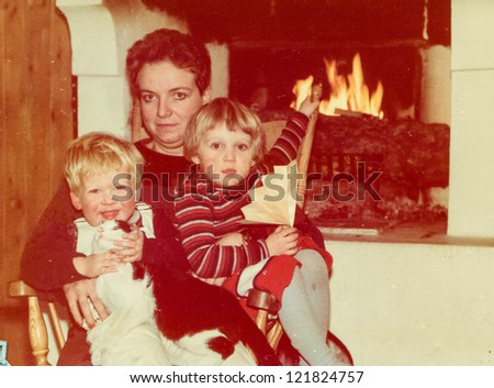 Vintage photo of mother with little children and cat near fireplace (early eighties)