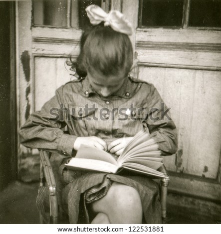 Vintage photo of young girl in scout uniform reading a book, early sixties