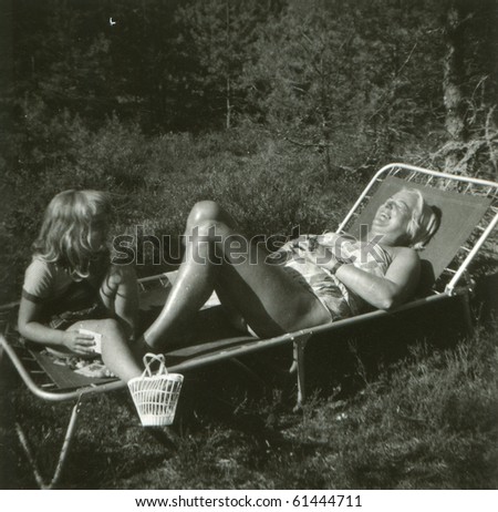 Vintage photo of mother and daughter on camping bed (fifties)