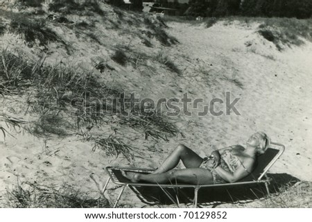 vintage unretouched photo of woman tanning on camping bed