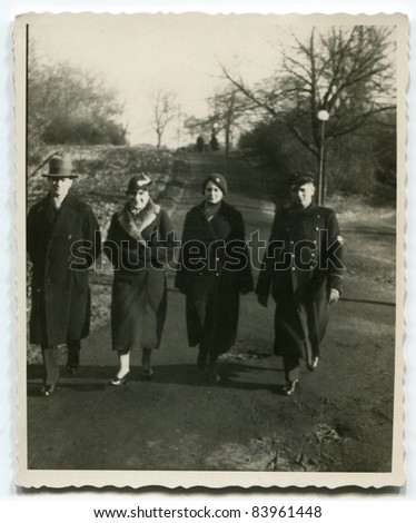 Vintage photo of  parents, son and daughter walking on the street (thirties)