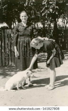 Vintage photo of grandmother and granddaughter with a dog, fifties