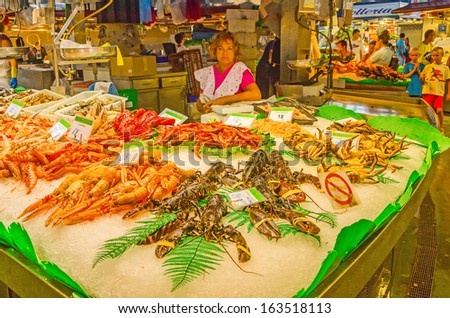BARCELONA, SPAIN - SEPTEMBER 6: Seller of seafood and her merchandise, La Boqueria food market on La Rambla, Barcelona, Spain on September 6, 2013