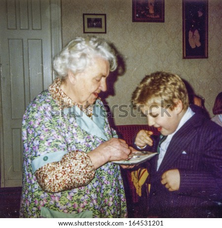 Vintage photo of great-grandmother and great-grandson blessing each other and sharing Christmas wafer during Christmas Eve Vigil, eighties
