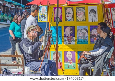 MONTREAL, CANADA, OCTOBER 12, 2013 - artist painting caricatures and his clients in the street of Old Montreal
