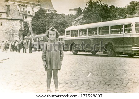POLAND, CIRCA FORTIES - Vintage photo of little girl with old bus in background