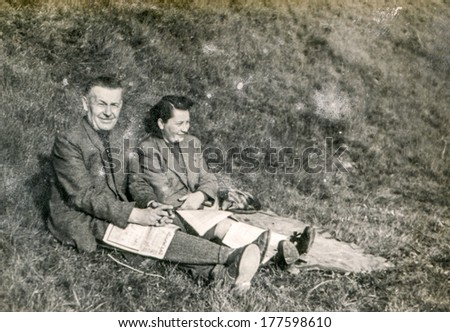POLAND, CIRCA FORTIES - vintage photo of happy couple reading newspapers outdoor