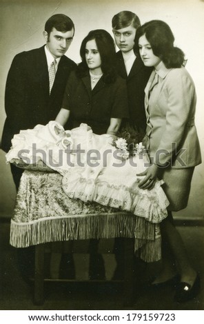 LODZ, POLAND,CIRCA SEVENTIES- vintage photo of parents and godparents with a baby in traditional baby\'s sleeping bag for christening