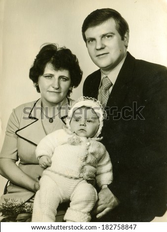 LODZ, POLAND, CIRCA MARCH 1982: vintage photo of parents with a baby at his christening