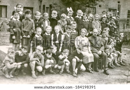 LODZ,POLAND, CIRCA 1950\'s: Vintage photo of group of  classmates and teachers posing together  in front of the school