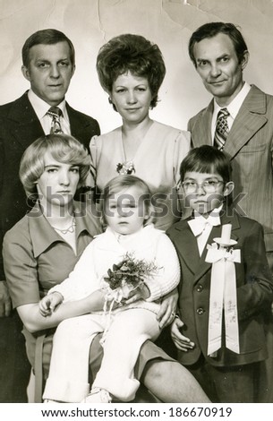 LODZ, POLAND, MAY 14, 1978: Vintage photo of boy at his First Communion posing with parents, god parents and little brother