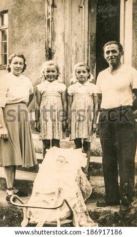 LODZ, POLAND, CIRCA 1950's: Vintage photo of parents with three daughters in front of their house