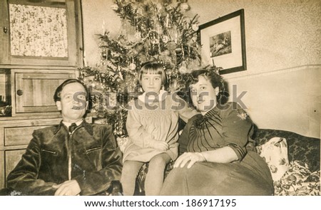 SCHWEINHEIM, GERMANY, DECEMBER 25, 1955: Vintage photo of parents with little daughter near Christmas tree