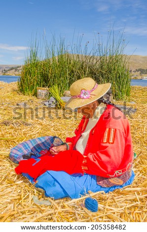 PUNO, PERU, MAY 5, 2014 - Women in traditional attire does some embroidery on floating Uros islands on Lake Titicaca