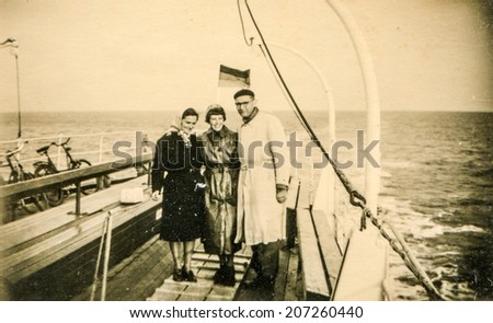 BUTJADINGEN, GERMANY, CIRCA FORTIES - Vintage photo of man and two women on boat