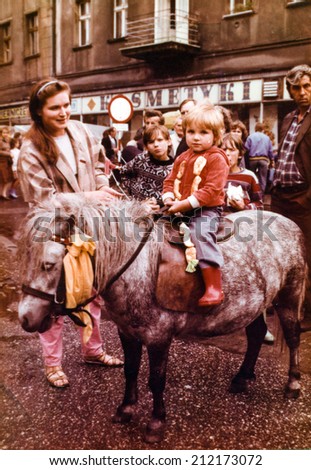 SOSNOWIEC, POLAND, AUGUST 1987 - Vintage photo of parents with their daughter posing on pony