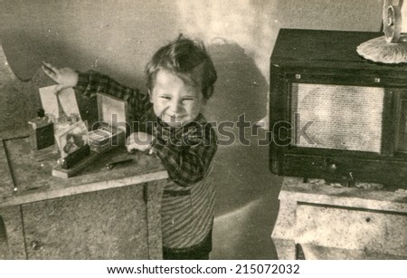 LODZ, POLAND, CIRCA FIFTIES: Vintage photo of little girl and old radio