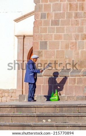 CUZCO, PERU, MAY 1, 2014: Elderly local man reads a poster in front of San Francisco church