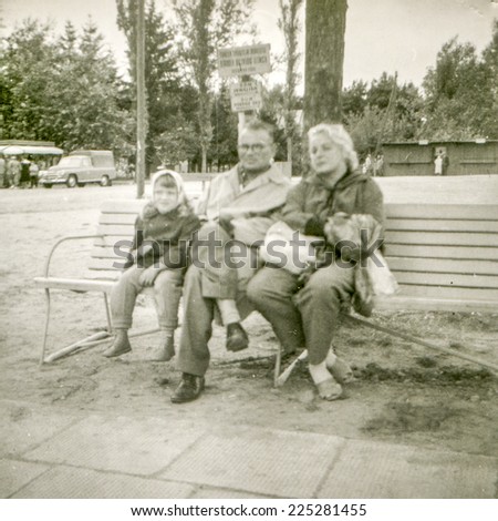 Vintage photo of parents sitting on bench with little daughter, fifties
