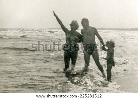Vintage photo of parents enjoying beach with little daughter, fifties