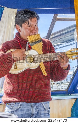 PUNO, PERU, MAY 5, 2014: Local man plays music on traditional instruments during boat trip to Uros Islands