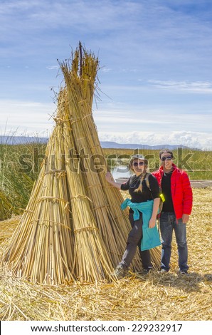 Lake Titicaca, Peru - Couple of tourists poses near reed bundle on one of floating islands