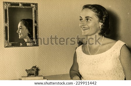 LODZ, POLAND, CIRCA FIFTIES - Vintage photo of young woman in front of mirror