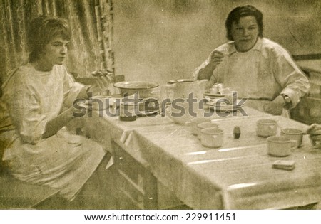 LODZ, POLAND, CIRCA FIFTIES - Vintage photo of two young female doctors eating breakfast in hospital