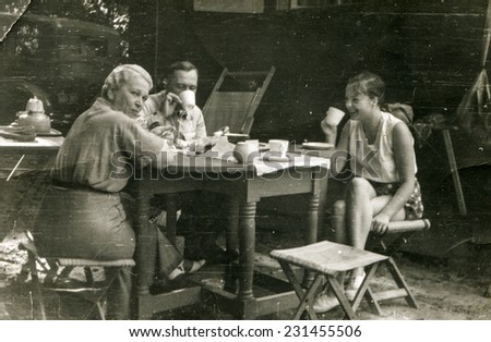 POLAND, CIRCA FORTIES: Vintage photo of parents with teenager daughter drinking tea in garden