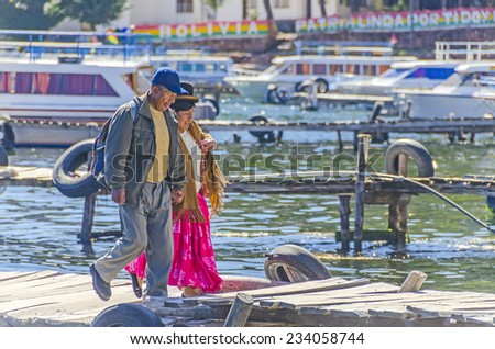 COPACABANA, BOLIVIA, MAY 7, 2014:  Local woman in traditional attire walks with her husband on jetty in port (Titicaca lake)