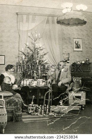 GERMANY, CIRCA DECEMBER 1924:  Vintage photo of family sitting near Christmas tree while Adolf Hitler portrait hangs on wall