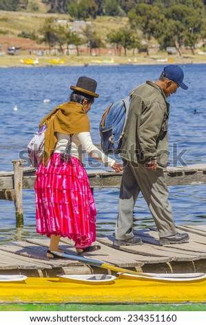 COPACABANA, BOLIVIA, MAY 7, 2014: Local woman in traditional attire walk with her husband on jetty in port (Titicaca lake)