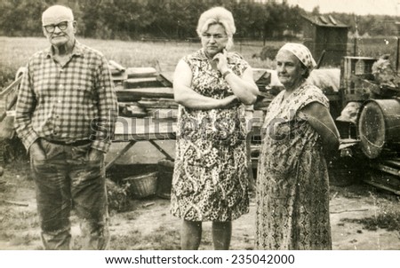 Vintage photo of farmers family (elderly parents and adult daughter) on farm, sixties