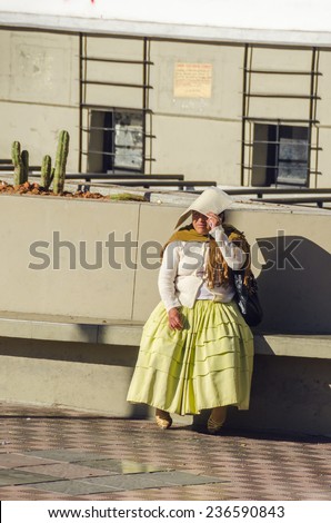 LA PAZ, BOLIVIA, MAY 8, 2014:  Local woman in traditional attire rests sitting on wall