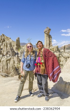 LA PAZ, BOLIVIA, MAY 9, 2014: Local man in traditional attire poses with young blond tourist in Moon Valley