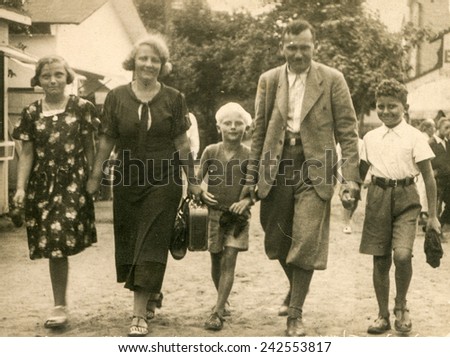 POLAND, CIRCA 1935: Vintage photo of parents with three children walking down the street