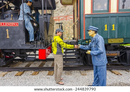 MOLLENDO, PERU, MAY 19, 2014:  Tourist shakes hands with a wax statue of rail worker in Ferro Carilles del Sur train open air museum