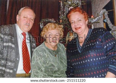 Vintage photo of elderly woman with her son and daughter in law in front of Christmas tree, nineties